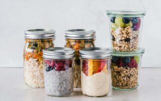 Close-up of healthy food jars containing granola, fruits, and yogurt.
