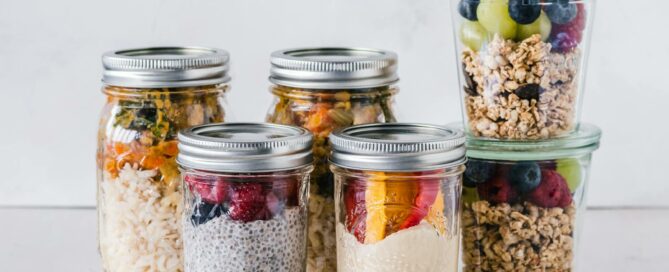 Close-up of healthy food jars containing granola, fruits, and yogurt.