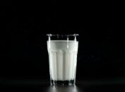 A glass of fresh milk against a black background, emphasizing simplicity and nutrition.