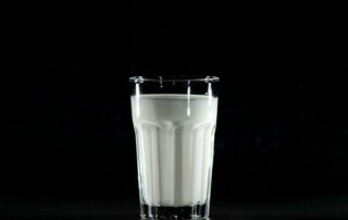 A glass of fresh milk against a black background, emphasizing simplicity and nutrition.